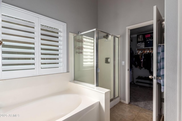 full bath with a garden tub, tile patterned flooring, a shower stall, and a walk in closet