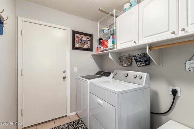 laundry area featuring washer and dryer, cabinet space, and light tile patterned floors