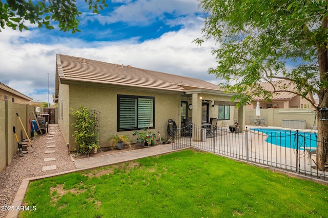 back of house with a fenced in pool, stucco siding, a lawn, a patio area, and a fenced backyard