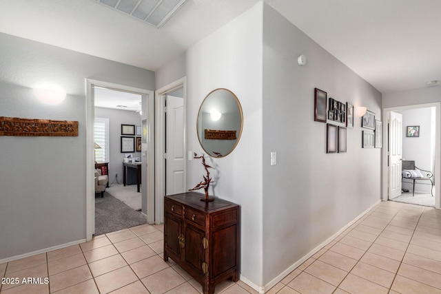 corridor featuring light tile patterned floors, visible vents, and baseboards