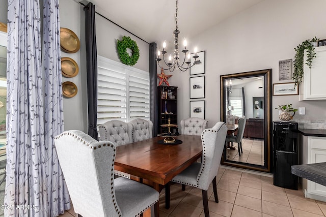 dining room with lofted ceiling, light tile patterned flooring, and an inviting chandelier