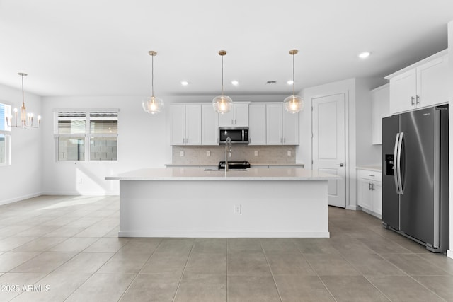 kitchen featuring a kitchen island with sink, decorative light fixtures, white cabinetry, and appliances with stainless steel finishes