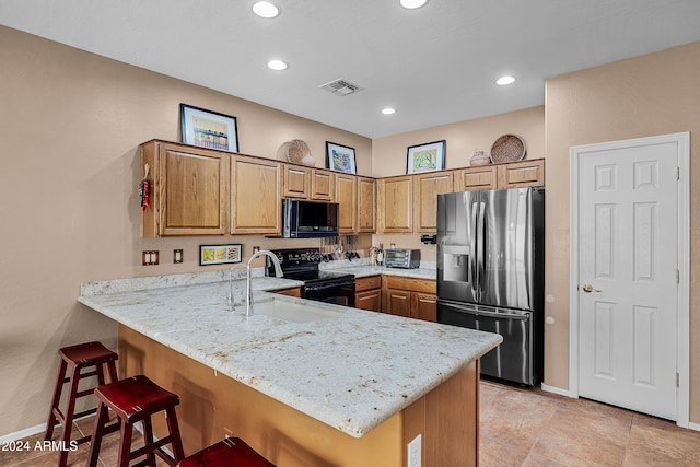 kitchen featuring a kitchen breakfast bar, kitchen peninsula, sink, and black appliances