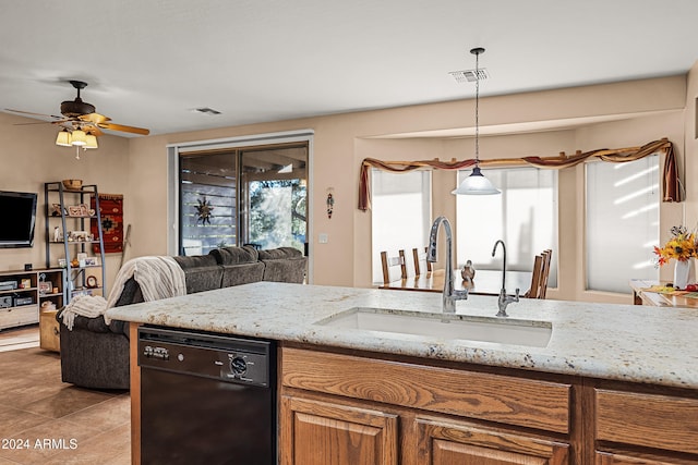 kitchen featuring light stone counters, sink, black dishwasher, and hanging light fixtures