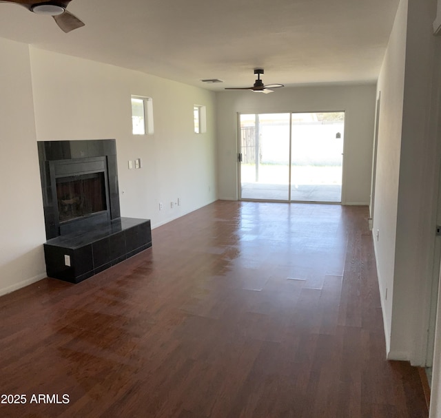 unfurnished living room featuring plenty of natural light, ceiling fan, wood finished floors, and a fireplace