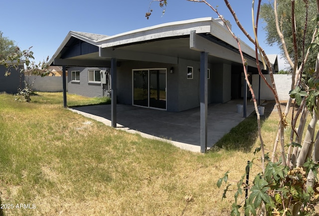 rear view of property with a lawn, fence, a patio, and stucco siding