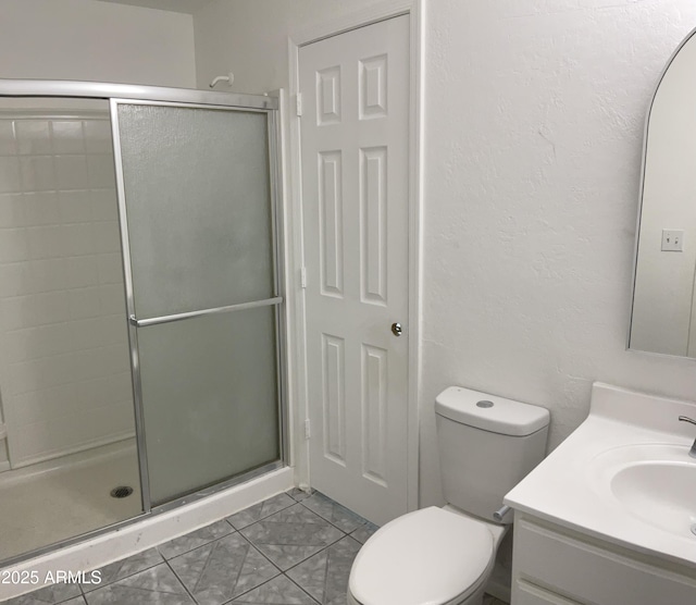 bathroom featuring toilet, a shower stall, tile patterned flooring, and vanity