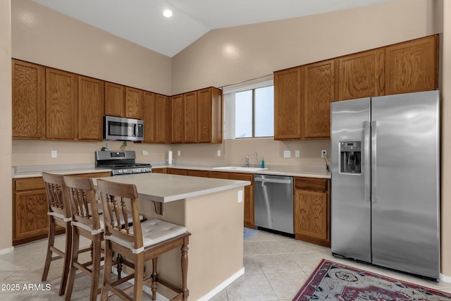 kitchen with a kitchen island, sink, a kitchen breakfast bar, light tile patterned floors, and stainless steel appliances