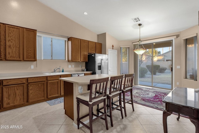 kitchen with pendant lighting, sink, lofted ceiling, appliances with stainless steel finishes, and a kitchen bar