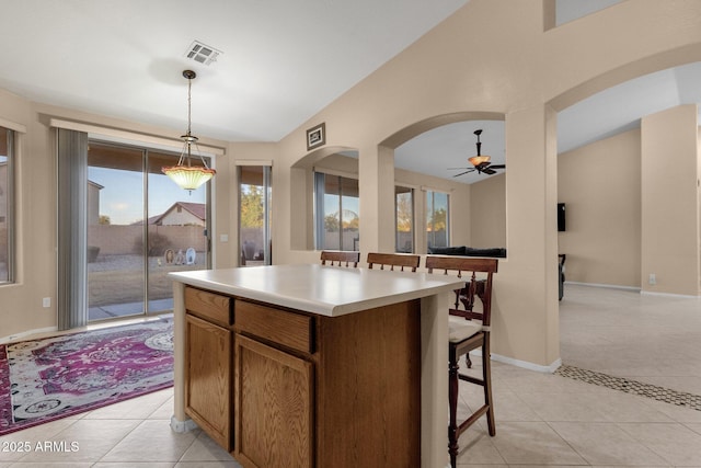 kitchen with vaulted ceiling, a center island, light tile patterned floors, and decorative light fixtures