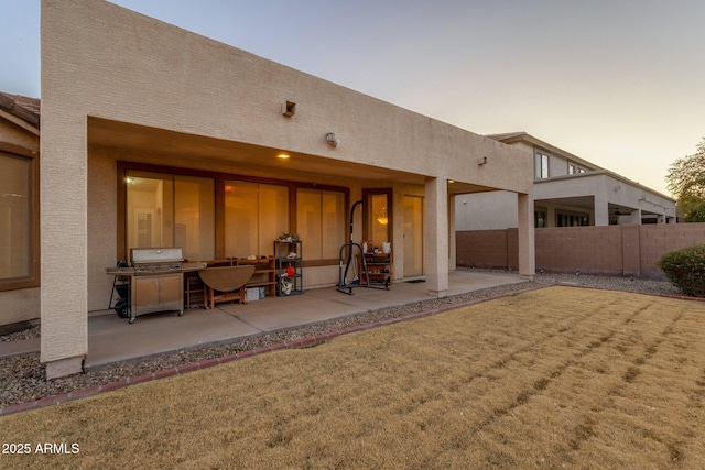 back house at dusk with a yard and a patio area