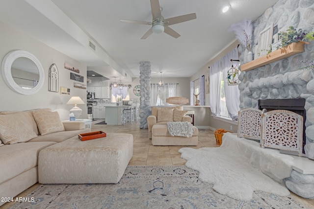 living room featuring light tile patterned floors, a stone fireplace, and ceiling fan