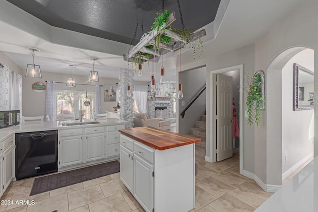 kitchen with white cabinets, pendant lighting, sink, a stone fireplace, and dishwasher