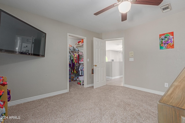 carpeted bedroom with ceiling fan, a closet, and a spacious closet