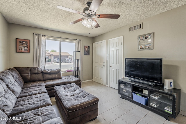 living room featuring a ceiling fan, light tile patterned flooring, a textured ceiling, and baseboards