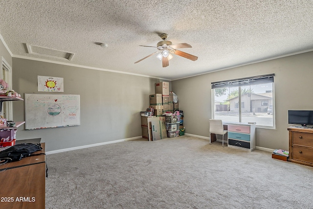 recreation room with a textured ceiling, ornamental molding, ceiling fan, carpet flooring, and attic access