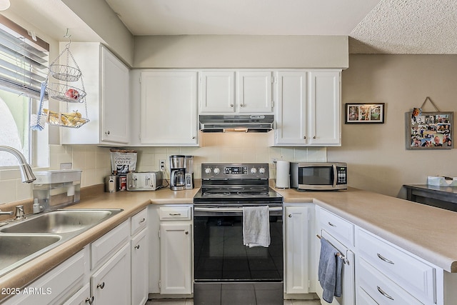 kitchen with electric range oven, under cabinet range hood, stainless steel microwave, a sink, and decorative backsplash