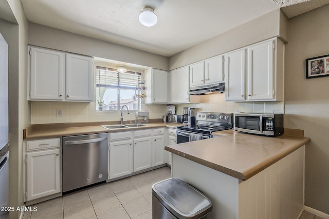 kitchen with appliances with stainless steel finishes, a sink, under cabinet range hood, and decorative backsplash