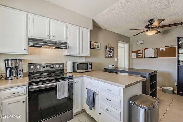 kitchen with appliances with stainless steel finishes, a peninsula, under cabinet range hood, light tile patterned floors, and a ceiling fan