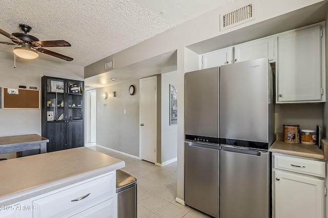 kitchen featuring freestanding refrigerator, white cabinetry, light tile patterned floors, light countertops, and a textured ceiling