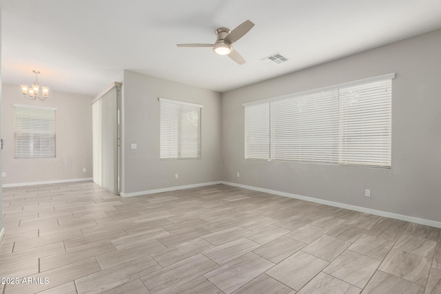 unfurnished room with ceiling fan with notable chandelier, visible vents, and baseboards