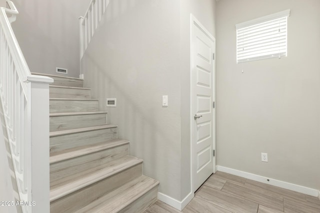 stairway featuring visible vents, wood finished floors, and baseboards