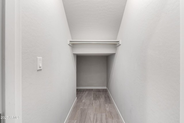 walk in closet with wood finished floors