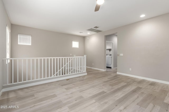 spare room featuring visible vents, baseboards, ceiling fan, light wood-type flooring, and washer / dryer