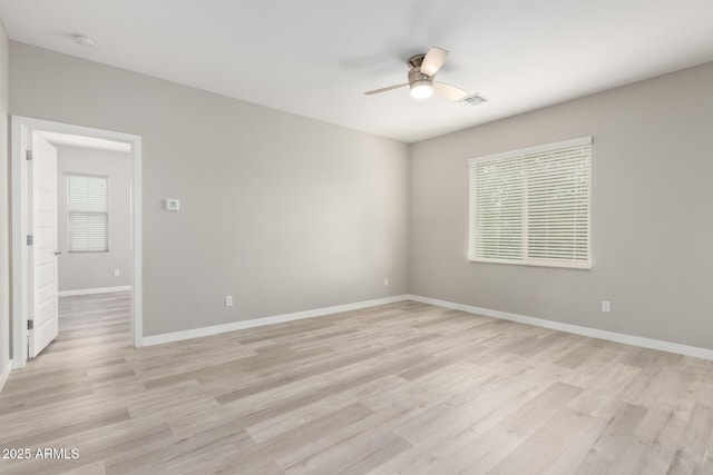 spare room featuring visible vents, light wood-style flooring, a ceiling fan, and baseboards