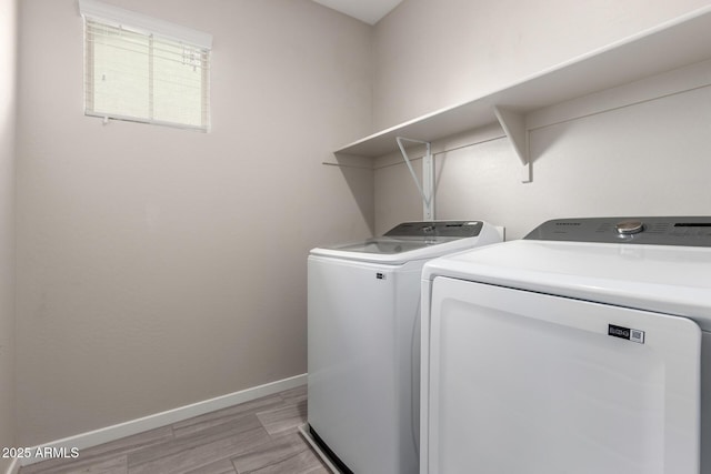 laundry area featuring laundry area, washing machine and dryer, light wood-style flooring, and baseboards