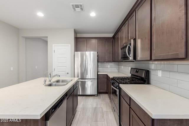 kitchen featuring visible vents, a sink, stainless steel appliances, light countertops, and dark brown cabinets