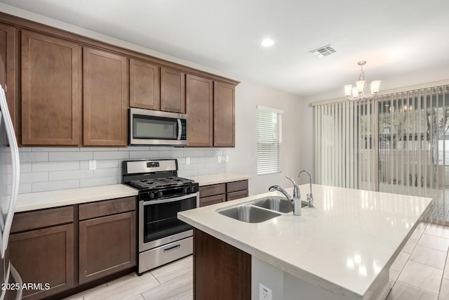 kitchen featuring visible vents, decorative backsplash, appliances with stainless steel finishes, an inviting chandelier, and a sink