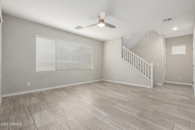 spare room with visible vents, baseboards, ceiling fan, and stairway