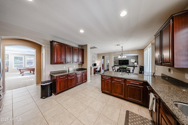 2886 E Hazeltine Way, Chandler, AZ 85249 - kitchen with recessed lighting, dark stone counters, a chandelier, arched walkways, and decorative light fixtures
