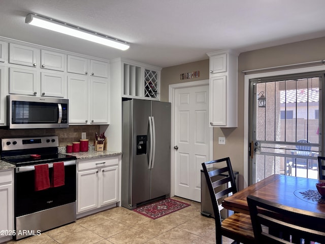 6049 S Wilson Dr, Chandler, AZ 85249 - kitchen with appliances with stainless steel finishes, white cabinetry, backsplash, light tile patterned floors, and light stone countertops