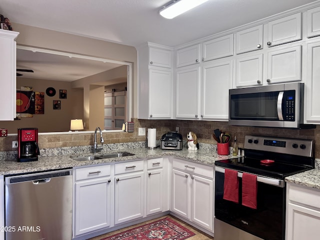 6049 S Wilson Dr, Chandler, AZ 85249 - kitchen with stainless steel appliances, a sink, white cabinetry, tasteful backsplash, and light stone counters
