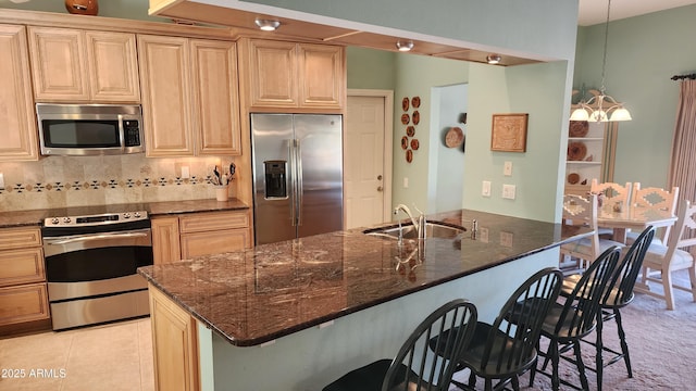 kitchen featuring sink, hanging light fixtures, a breakfast bar, and appliances with stainless steel finishes