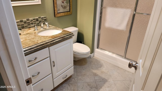 bathroom featuring toilet, vanity, decorative backsplash, and a shower with shower door