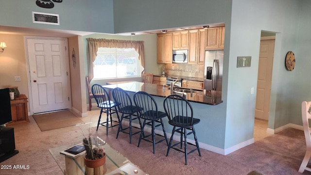 kitchen featuring sink, a breakfast bar, appliances with stainless steel finishes, tasteful backsplash, and light carpet