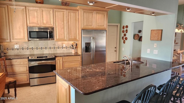 kitchen featuring light tile patterned flooring, sink, dark stone countertops, decorative backsplash, and stainless steel appliances