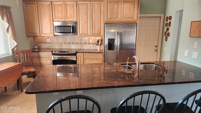 kitchen with sink, light tile patterned floors, dark stone countertops, stainless steel appliances, and decorative backsplash