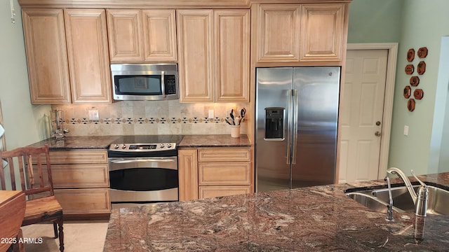 kitchen featuring appliances with stainless steel finishes, sink, and dark stone counters