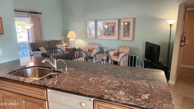 kitchen with white dishwasher, sink, tile patterned floors, and dark stone counters