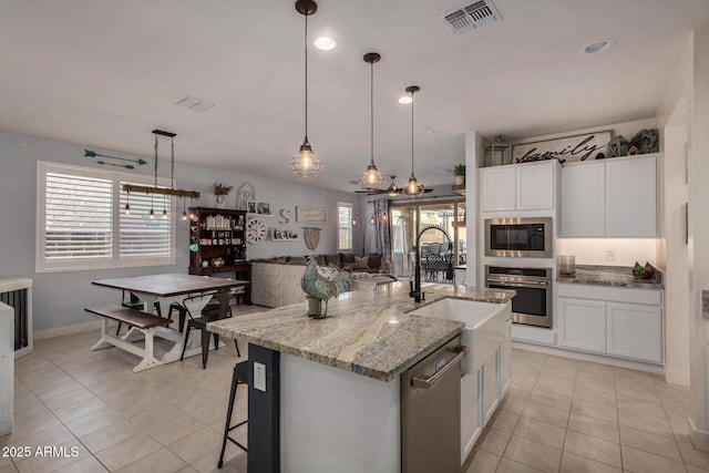 kitchen with appliances with stainless steel finishes, pendant lighting, an island with sink, and white cabinetry