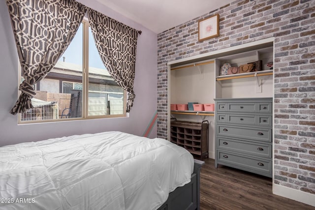 bedroom featuring brick wall, a closet, and dark hardwood / wood-style floors