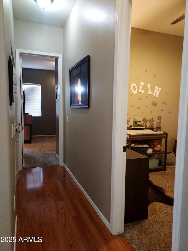 hall with dark wood-type flooring and baseboards