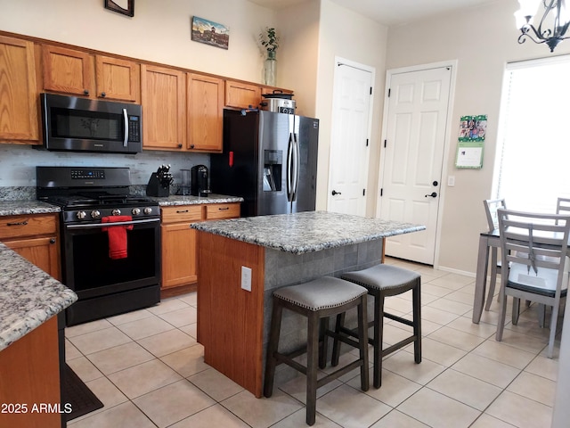 kitchen featuring stainless steel fridge with ice dispenser, light tile patterned floors, black gas range, decorative backsplash, and a breakfast bar area