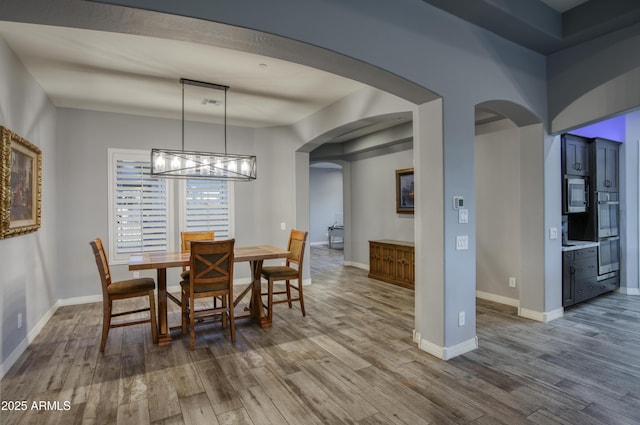18175 W Highland Ave, Goodyear, AZ 85395 - dining area featuring arched walkways, baseboards, and wood finished floors