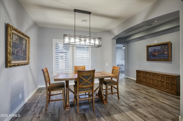 18175 W Highland Ave, Goodyear, AZ 85395 - dining area featuring visible vents, baseboards, dark wood-type flooring, a chandelier, and arched walkways
