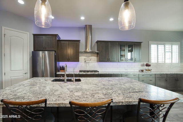 18175 W Highland Ave, Goodyear, AZ 85395 - kitchen featuring wall chimney range hood, dark brown cabinets, appliances with stainless steel finishes, a sink, and a kitchen breakfast bar